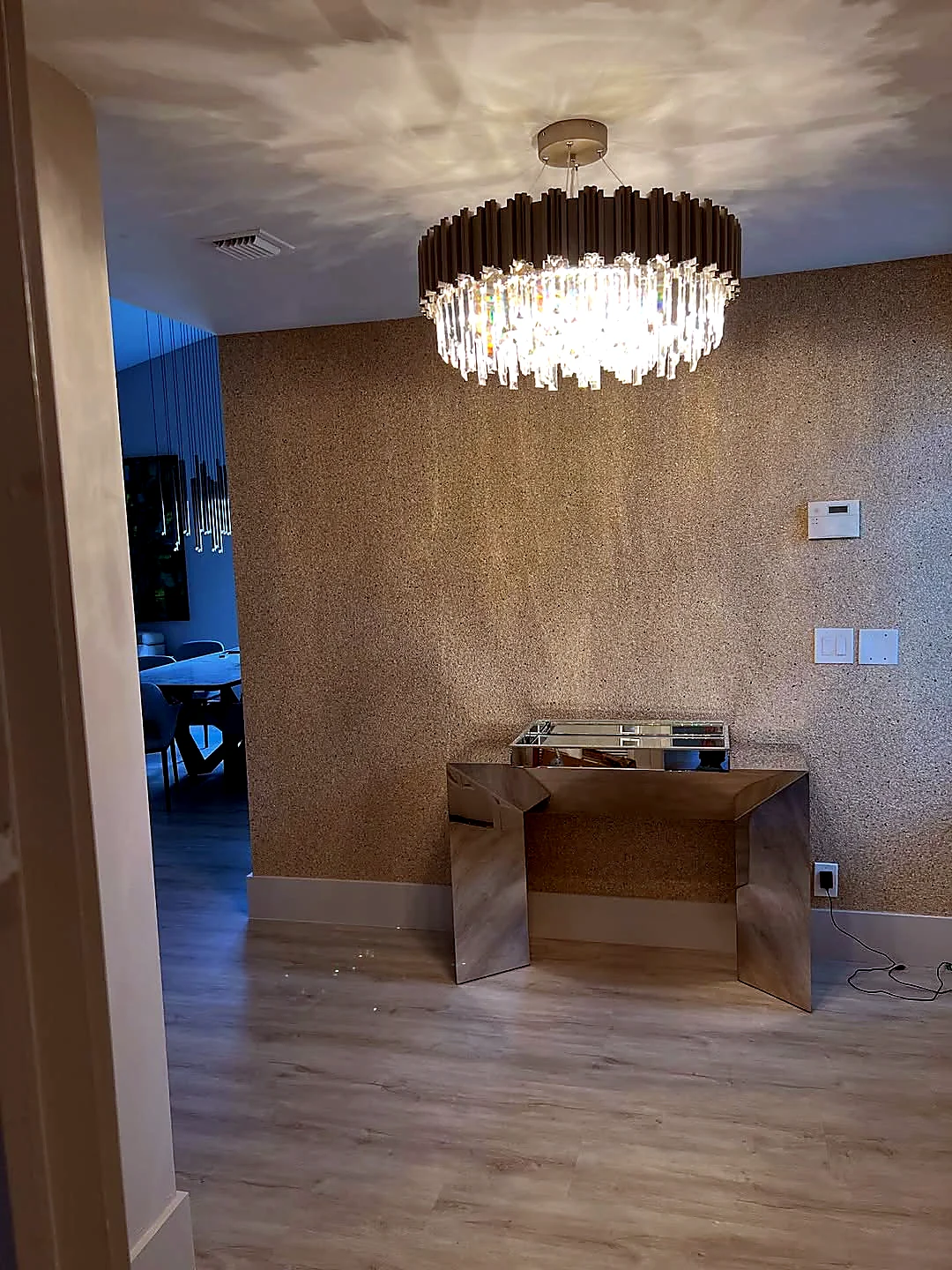 Textured specialty wallcovering installed in an entry hall under a crystal chandelier